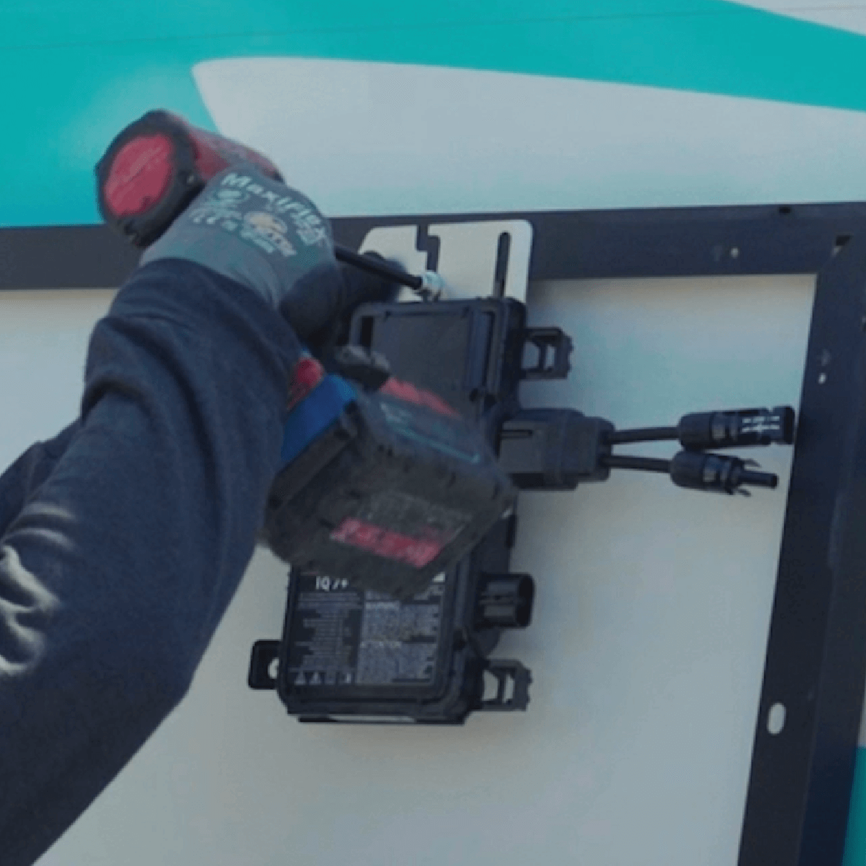 Solar expert securing a microinverter to the back of a panel using power tools