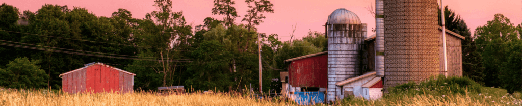Wisconsin at sunset, including an open field with a small barn and silo