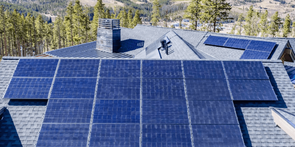 Large residential solar panel system installed with trees and mountains in the background