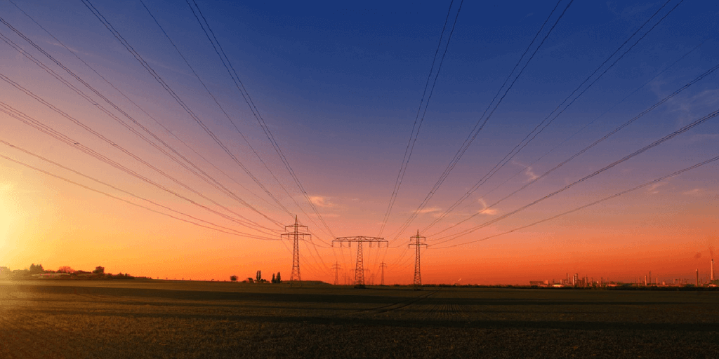 Utility lines with a vibrant sunset in the background ranging from dark blue to yellow