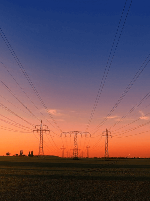 Utility lines with a vibrant sunset in the background ranging from dark blue to yellow