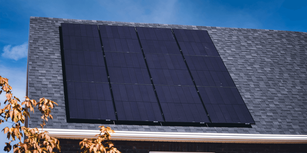 Custom solar panel array, installed on a grey-shingle roof with autumn leaves in the bottom left hand corner