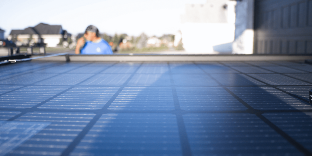 A Guide to Solar Panel Efficiency and Performance-02 Up close view of solar cells in a solar panel system at a job site with an installer in the background