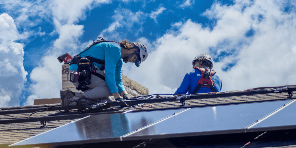 Two Blue Raven Solar installers on a roof, placing the racking for a customized, rooftop solar panel system