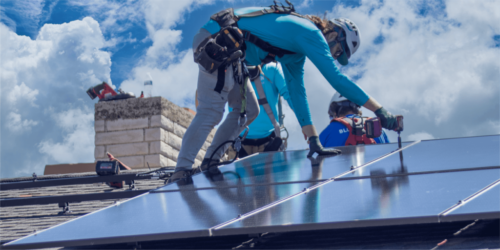 6 Reasons to Choose Blue Raven Solar-01 Blue Raven Solar installers securing a monocrystalline solar panel to a roof using specialized tools and racking
