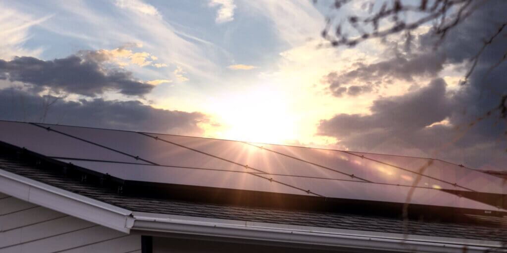 Blue Raven Solar install with sun beaming above the roof line, between thick clouds