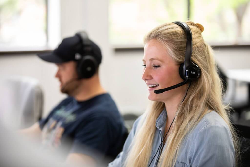 Blue Raven Staged Photos -4 Female Blue Raven Solar support representative with headset, talking on the phone with a customer and a male colleague next